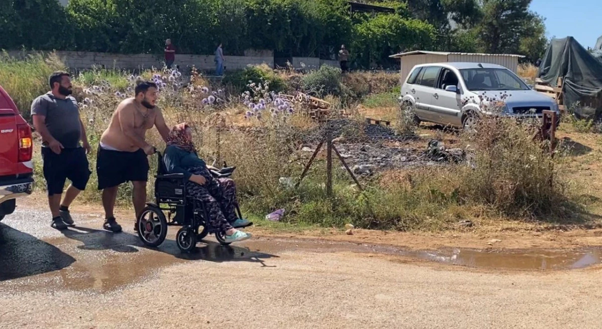 EVİNE YAKLAŞAN ALEVLERDEN KURTARILAN KADIN TEKERLEKLİ SANDALYEYLE BÖLGEDEN UZAKLAŞTIRILDI